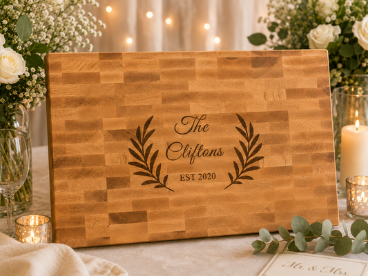 Wooden cutting board with engraved text 'The Cliftons EST 2020' on a decorative table setting.