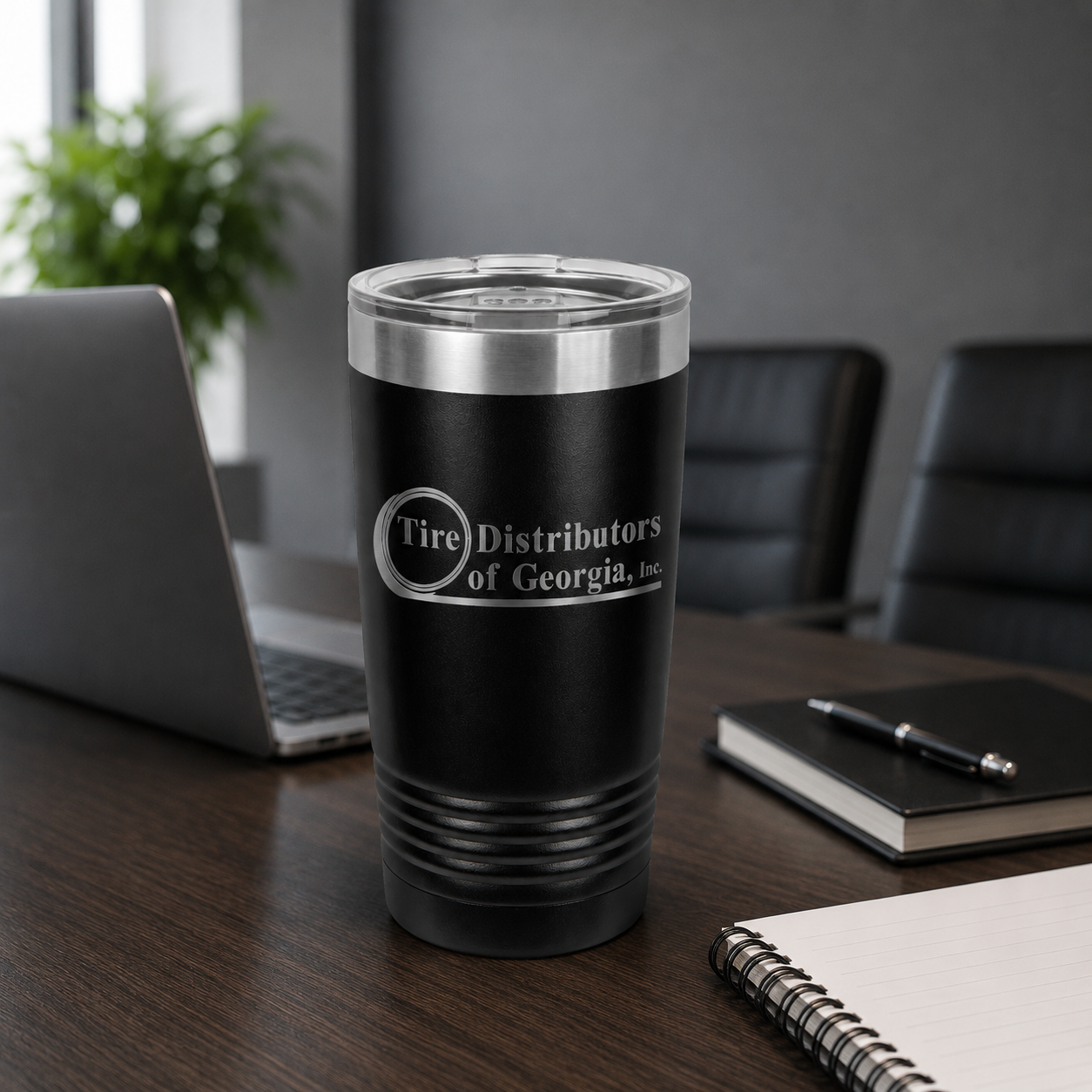 Black tumbler with 'Tire Distributors of Georgia, Inc.' logo on a desk in an office setting.