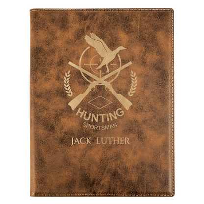 Brown leather notebook with hunting-themed design and engraved text on a white background