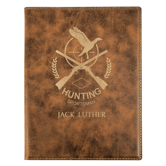 Brown leather notebook with hunting-themed design and engraved text on a white background